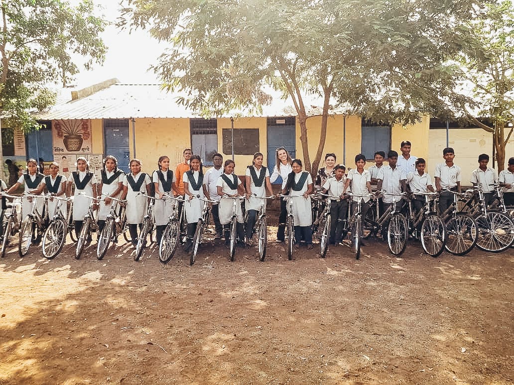 Students standing with bicycles outside a school in India